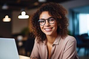 Portrait of a Beautiful Diverse Female Wearing Glasses, Using Laptop Computer, Looking at Camera and Smiling. Information Technology Specialist, Software Engineer or Developer. photo