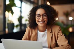 Portrait of a Beautiful Diverse Female Wearing Glasses, Using Laptop Computer, Looking at Camera and Smiling. Information Technology Specialist, Software Engineer or Developer. photo