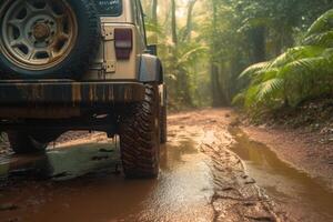 Four wheel drive SUV is driving on muddy road in jungle. photo