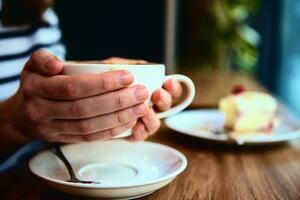 Woman have breakfast at cafe, hold coffee cap in hands photo