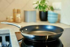 Frying pan on induction hob at kitchen photo