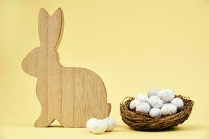 Happy Easter decoration, Wooden rabbit and eggs on yellow background photo