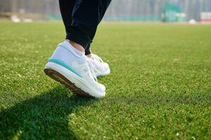 Runner feet running at stadium with green grass photo