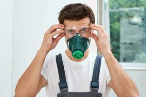 Portrait of home repair worker. Renovation handyman with protective glasses and respirator photo