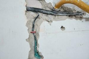 viejos cables eléctricos en una pared de ladrillos. cableado de peligro foto