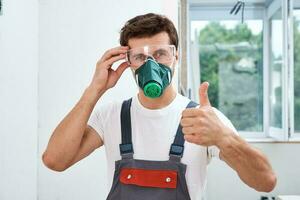 Portrait of home repair worker. Renovation handyman with protective glasses and respirator photo