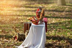 Samovar with bagel on white tablecloth. Side view. Sack on grass in forest. Shrovetide, folk festival photo