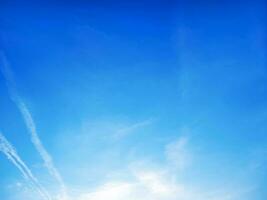 The background is pure blue sky with soft transparent clouds. Trace of the plane. copy space photo