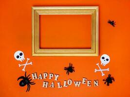 Halloween decorations on an orange background. Trinkets, a Happy Halloween inscription and a frame with a place for text photo