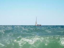 yate navegación en abierto mar a soleado día. navegación Embarcacion yate con blanco paño a abrió mar en Ventoso condición foto