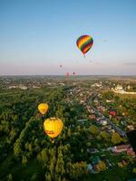 July 23, 2022 Russia, Pereslavl-Zalessky. Aeronautics festival, big balloons with baskets flying over houses and church photo