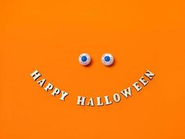 Scary and funny eyes and Happy Halloween inscription on an orange background, copy the space, Flat layout, top view photo