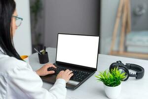 A focused girl works on a laptop with an isolated screen for mockup. Business scene on an office desk photo