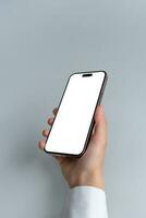 Hand holds a smartphone with blank, isolated screen against a grey background. Isolated screen for mockup, app or web page presentation photo