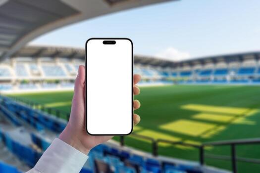 Mockup of phone in hand in modern stadium. Isolated screen for adding an app or website. Empty stadium with seats and grass in background photo