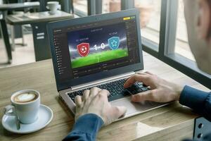 Man follows the soccer match result on a laptop. Concept of online betting and live score photo