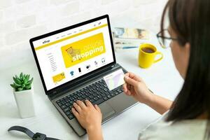 mujer utilizar crédito tarjeta a compras en línea con ordenador portátil en comercio electrónico web sitio foto