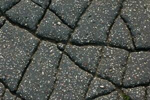 un red de negro grietas en el asfalto superficie. la carretera textura con resistido superficie, exhibiendo el efectos de hora y tener puesto. foto