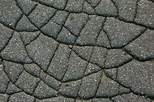 un red de negro grietas en el asfalto superficie. la carretera textura con resistido superficie, exhibiendo el efectos de hora y tener puesto. foto