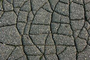 A network of black cracks on the asphalt surface. Road texture with weathered surface, showcasing the effects of time and wear. photo