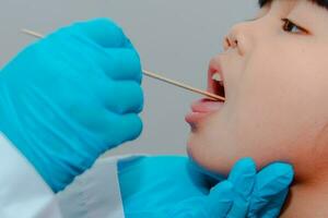 The doctor uses a tongue depressor to examine the child's tongue. photo