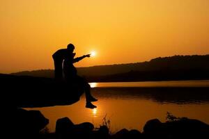 Silhouette of a person on a rock near the reservoir photo