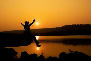 Silhouette of a person on a rock near the reservoir photo