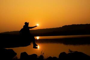 Silhouette of a person on a rock near the reservoir photo