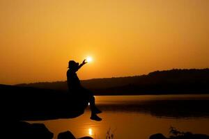 Silhouette of a person on a rock near the reservoir photo