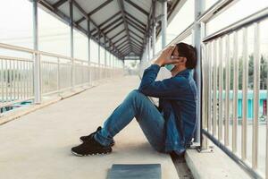 Stressed Asian man sitting on a footbridge photo