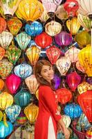 happy woman wearing Ao Dai Vietnamese dress with colorful lanterns, traveler sightseeing at Hoi An ancient town in central Vietnam.landmark for tourist attractions.Vietnam and Southeast travel concept photo