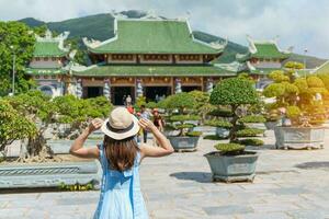 Woman traveler visiting at Linh Ung Pagoda temple or Lady big Buddha. Tourist with blue dress and hat traveling in Da Nang city. Vietnam and Southeast Asia travel concept photo