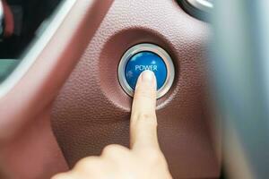 Finger press a car ignition button or START engine inside modern electric automobile. Keyless, change, strategy, vision, innovation and future concept photo