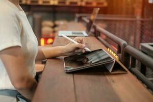 woman using tablet for sms messages, hand holding pencil typing touchscreen mobile phone in cafe or modern office. lifestyle, technology, Social media and network concept photo