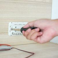 Man hand using screwdriver installing Wire cables for socket plug. Renovation, Repair, fixing and development of home and apartment concepts photo