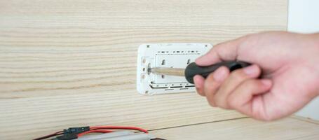 Man hand using screwdriver installing Wire cables for socket plug. Renovation, Repair, fixing and development of home and apartment concepts photo