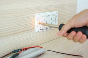 Man hand using screwdriver installing Wire cables for socket plug. Renovation, Repair, fixing and development of home and apartment concepts photo