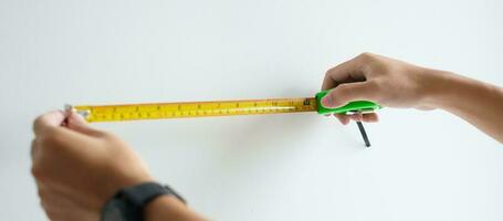 Man hand using tape measure for measuring with wall backgrounds at home. DIY, Interior design, repairing and improvement home or apartment concepts photo