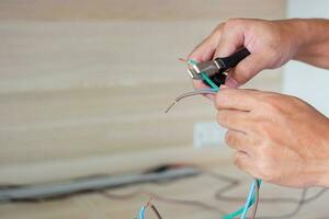 Electrician cuts electrical wires with pliers, Wiring cables installation for socket plug. Fixing, Renovation, Repair, service and development of home and apartment concepts photo