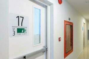 Fire extinguisher system on the wall with Fire Exit door sign for emergency. Stairwell fire for escape in building or apartment photo