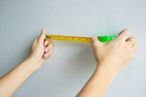 Man hand using tape measure for measuring with wall backgrounds at home. DIY, Interior design, repairing and improvement home or apartment concepts photo