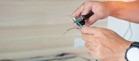 Electrician cuts electrical wires with pliers, Wiring cables installation for socket plug. Fixing, Renovation, Repair, service and development of home and apartment concepts photo