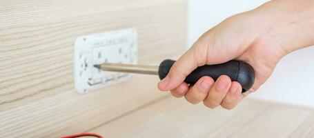 Man hand using screwdriver installing Wire cables for socket plug. Renovation, Repair, fixing and development of home and apartment concepts photo