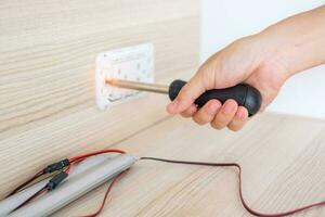 Man hand using screwdriver installing Wire cables for socket plug. Renovation, Repair, fixing and development of home and apartment concepts photo