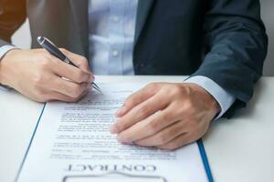 Businessman signing on contract documents after reading, man holding pen and approve on business report. Contract agreement, partnership and deal concepts photo