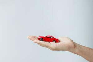 businessman hand holding red car toy. Car insurance, warranty, rental, Financial, new and repair concept photo