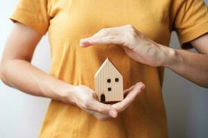 woman hand cover wooden Home model. real estate, insurance and property concepts photo