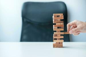 Businessman hand placing or pulling wooden block on the tower. Business planning, Risk Management, Solution and strategy Concepts photo