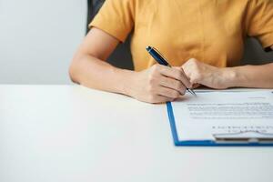 Woman signing on contract documents after reading, hand holding pen and approve on business report. Contract agreement, partnership and deal concepts photo