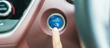 Finger press a car ignition button or START engine inside modern electric automobile. Keyless, change, strategy, vision, innovation and future concept photo